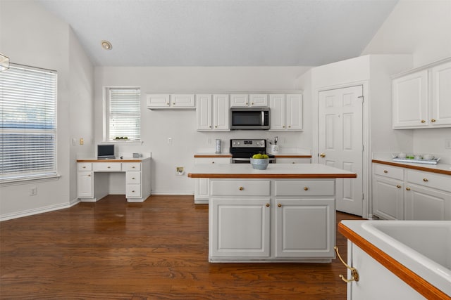 kitchen with appliances with stainless steel finishes, lofted ceiling, dark hardwood / wood-style floors, and white cabinets