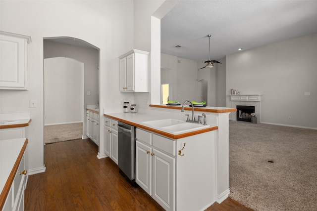 kitchen featuring dishwasher, kitchen peninsula, a tile fireplace, sink, and white cabinets