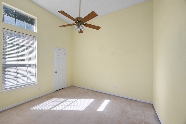 spare room with light colored carpet, a textured ceiling, high vaulted ceiling, and ceiling fan