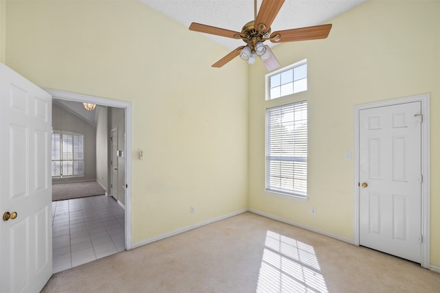 carpeted spare room with a textured ceiling, high vaulted ceiling, and ceiling fan