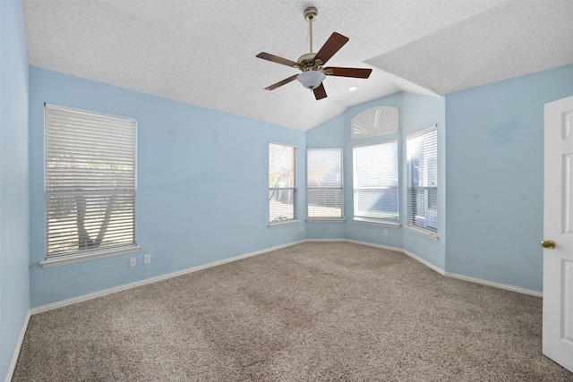 carpeted spare room featuring lofted ceiling, a textured ceiling, a healthy amount of sunlight, and ceiling fan