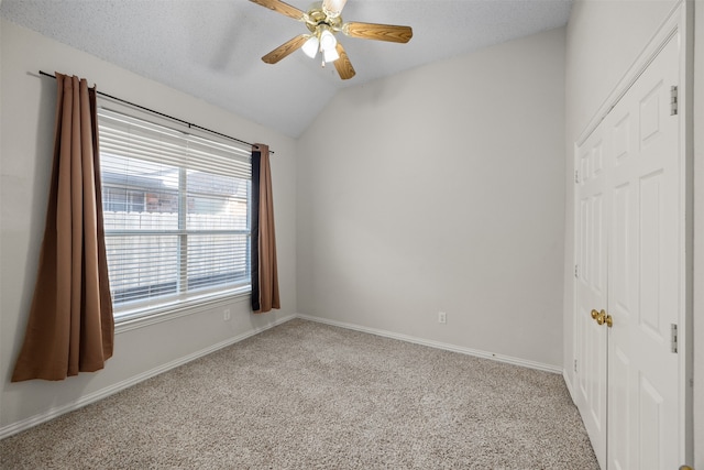 carpeted empty room with a textured ceiling, ceiling fan, and vaulted ceiling