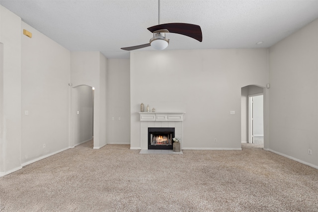 unfurnished living room featuring light carpet, a textured ceiling, a fireplace, and ceiling fan