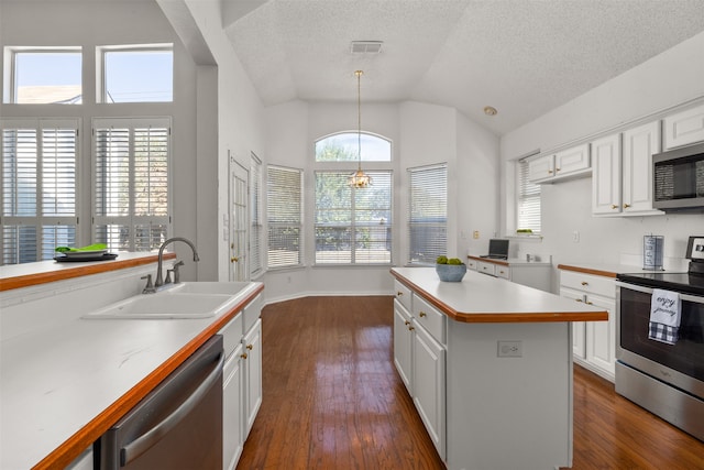 kitchen featuring appliances with stainless steel finishes, sink, a center island, dark hardwood / wood-style flooring, and white cabinetry