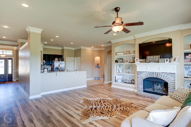 living room featuring crown molding, a brick fireplace, dark hardwood / wood-style floors, and ceiling fan