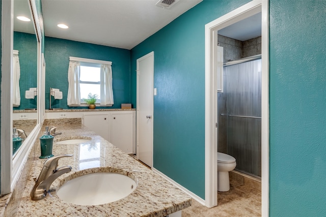 bathroom featuring toilet, a shower with shower door, vanity, and tile patterned floors