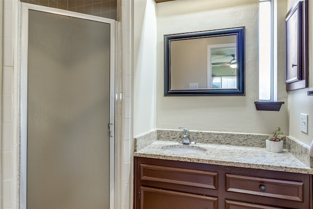 bathroom featuring a shower with door, vanity, and ceiling fan