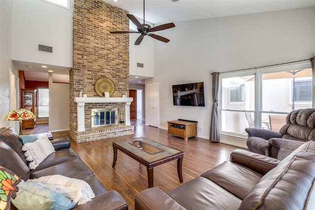 living room featuring ceiling fan, high vaulted ceiling, wood-type flooring, and a fireplace