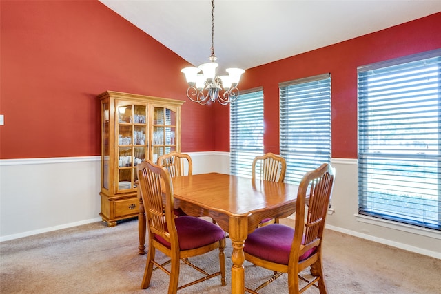 dining room with light carpet, lofted ceiling, and a chandelier