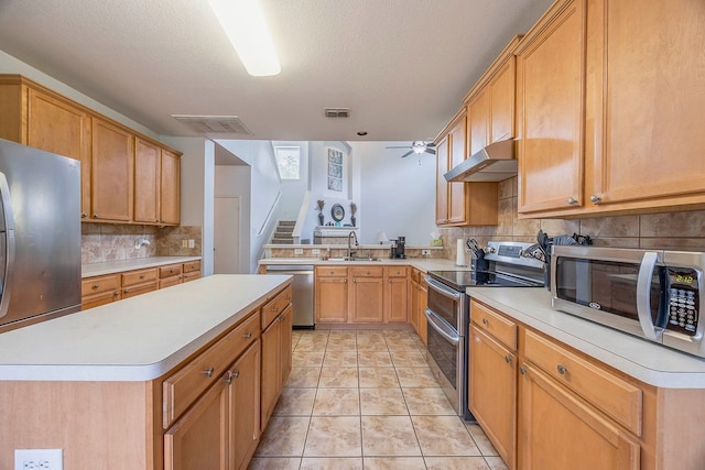 kitchen featuring appliances with stainless steel finishes, tasteful backsplash, ceiling fan, light tile patterned floors, and a center island