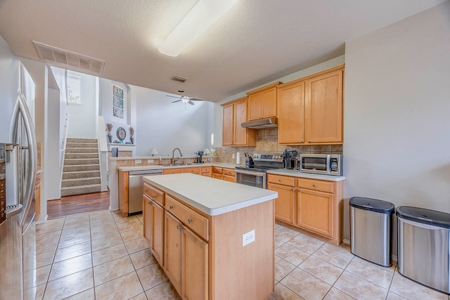 kitchen featuring light tile patterned flooring, a kitchen island, backsplash, appliances with stainless steel finishes, and kitchen peninsula