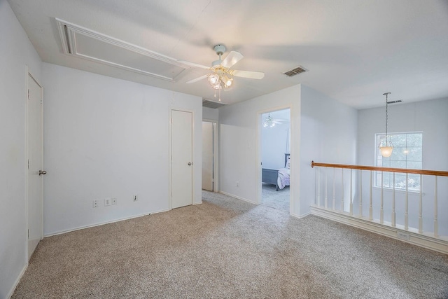 spare room featuring light colored carpet and ceiling fan with notable chandelier