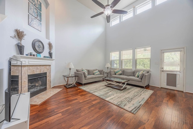 living room with a healthy amount of sunlight, a towering ceiling, and dark hardwood / wood-style floors