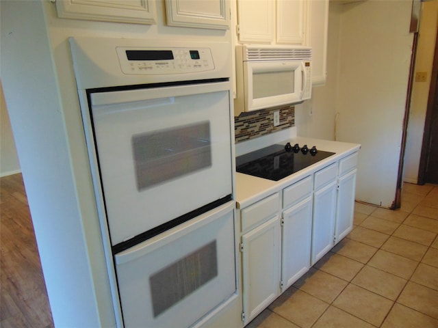 kitchen featuring white cabinetry, light tile patterned floors, and white appliances