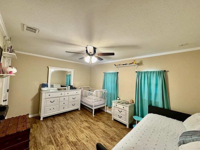 bedroom featuring crown molding, a textured ceiling, ceiling fan, and light wood-type flooring