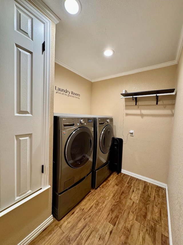 washroom featuring crown molding, independent washer and dryer, and light hardwood / wood-style floors