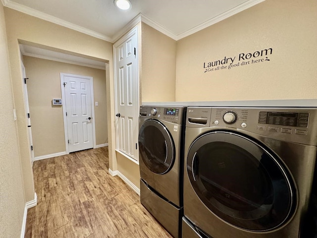 clothes washing area with crown molding, separate washer and dryer, and light wood-type flooring