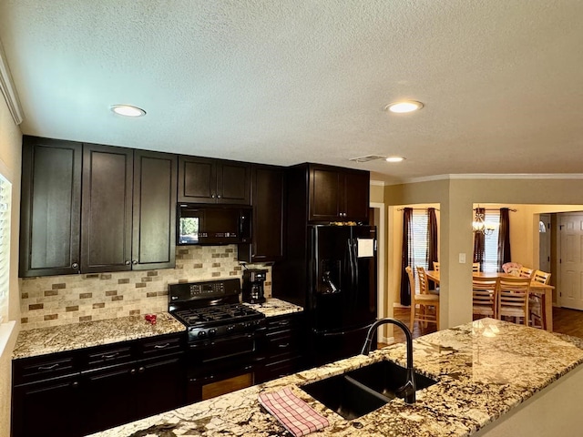 kitchen featuring decorative backsplash, light stone counters, crown molding, sink, and black appliances