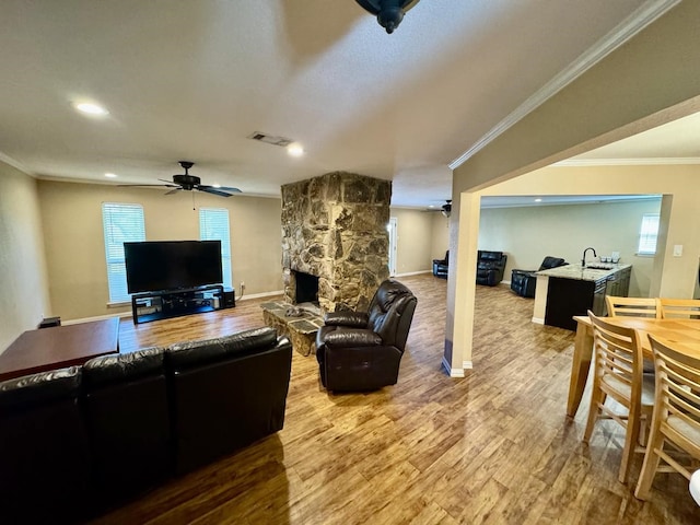 living room with ceiling fan, crown molding, hardwood / wood-style floors, and a fireplace