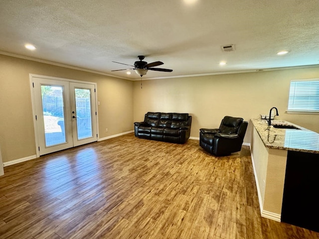 sitting room featuring sink, light hardwood / wood-style flooring, a textured ceiling, and french doors