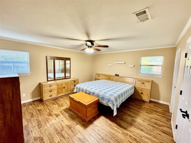 bedroom with ornamental molding, ceiling fan, a textured ceiling, and light wood-type flooring