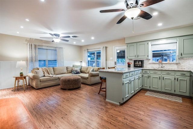 kitchen featuring tasteful backsplash, green cabinets, kitchen peninsula, and light hardwood / wood-style floors