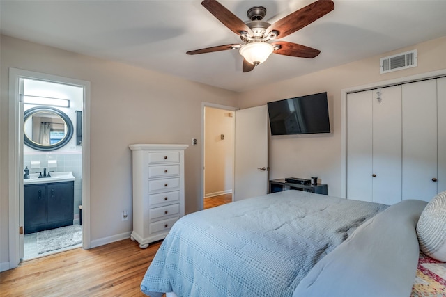 bedroom featuring ensuite bathroom, sink, ceiling fan, light hardwood / wood-style floors, and a closet