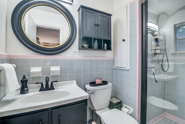 bathroom with vanity, toilet, a shower with door, and tile walls