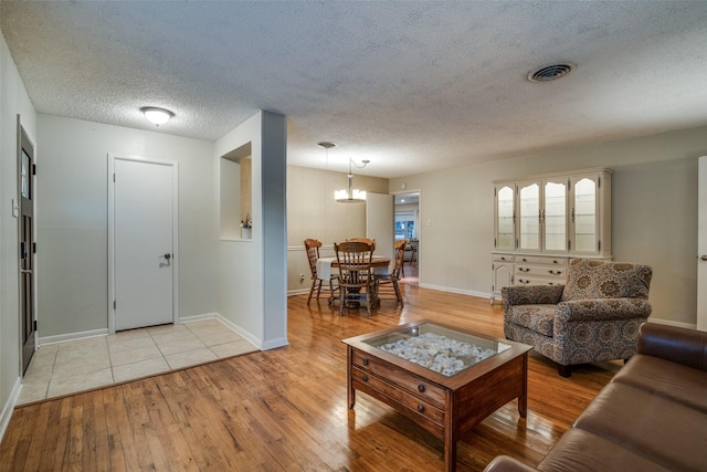 living room featuring a chandelier, a textured ceiling, and light hardwood / wood-style flooring