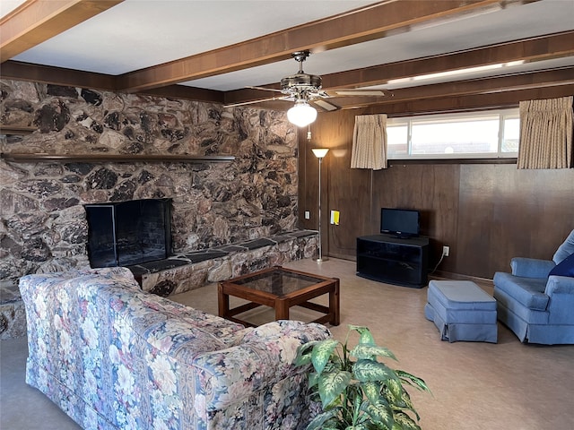 living room with wood walls, ceiling fan, beam ceiling, a fireplace, and light colored carpet