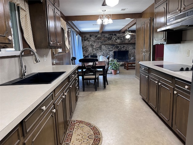 kitchen featuring black electric cooktop, sink, beamed ceiling, dark brown cabinets, and a fireplace