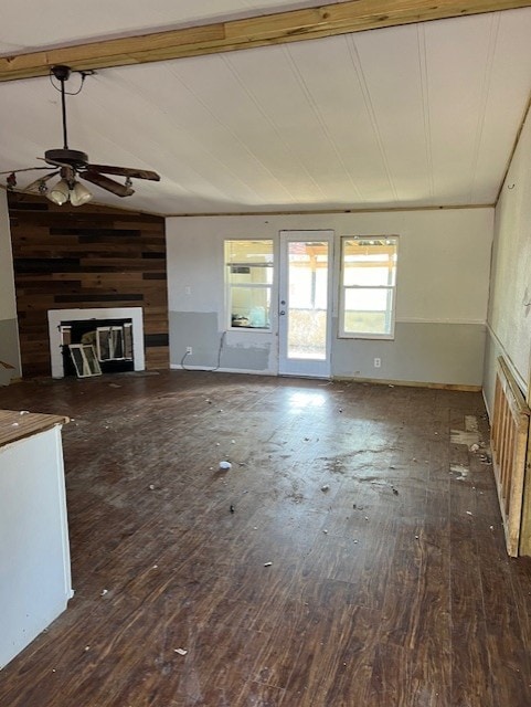 unfurnished living room featuring dark hardwood / wood-style flooring, lofted ceiling with beams, and ceiling fan