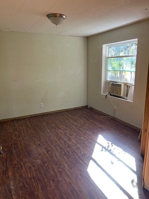 spare room featuring cooling unit and dark wood-type flooring