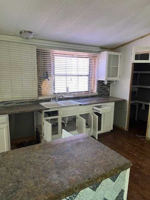 kitchen with dark wood-type flooring, sink, vaulted ceiling, decorative backsplash, and white cabinetry