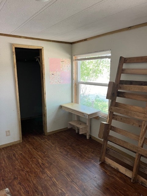 unfurnished bedroom with a textured ceiling, dark hardwood / wood-style flooring, and a spacious closet