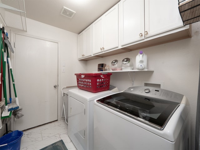 clothes washing area with cabinets and washing machine and clothes dryer