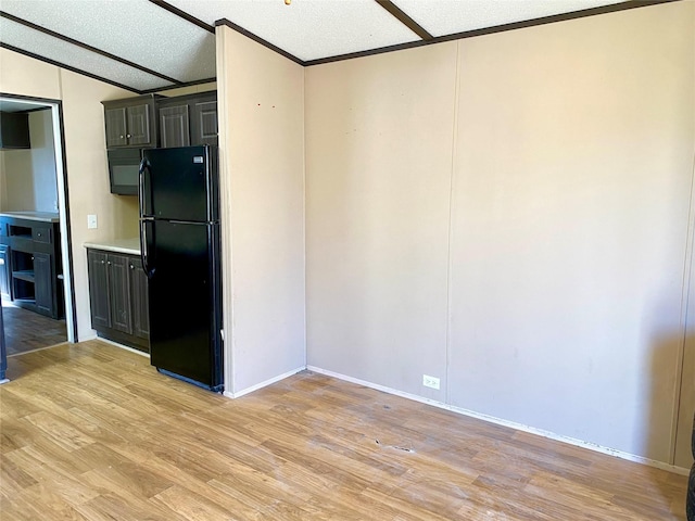 kitchen with vaulted ceiling, black fridge, a textured ceiling, and light hardwood / wood-style floors