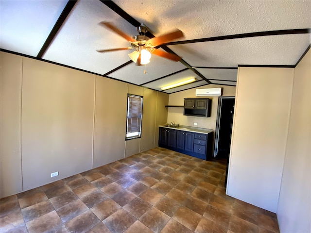 kitchen with ceiling fan, a textured ceiling, vaulted ceiling, a wall mounted air conditioner, and sink