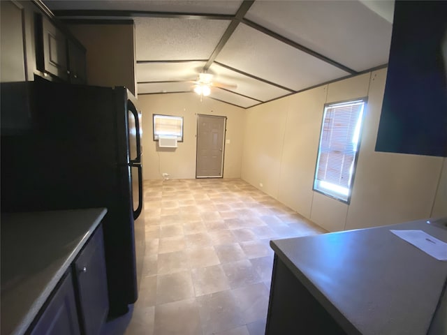 kitchen featuring plenty of natural light, ceiling fan, vaulted ceiling, and black fridge