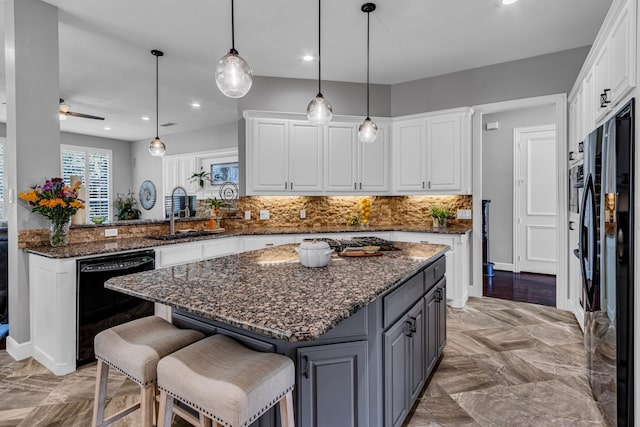 kitchen featuring sink, dishwasher, kitchen peninsula, dark stone counters, and white cabinets