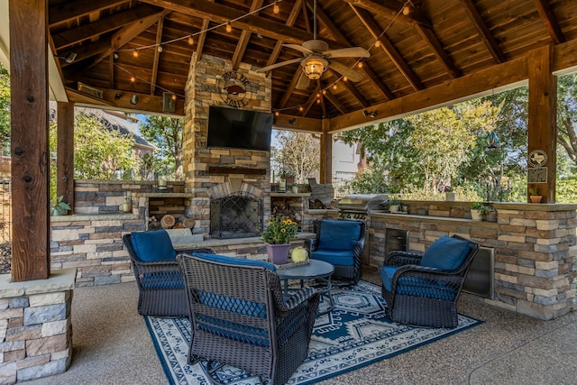 view of patio featuring area for grilling, an outdoor stone fireplace, exterior kitchen, a gazebo, and ceiling fan