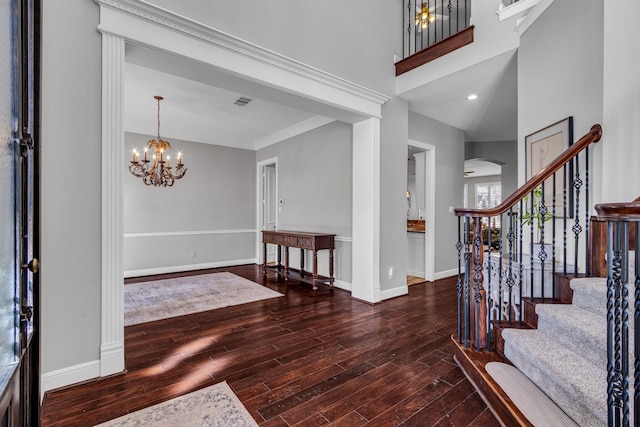 foyer entrance featuring crown molding, a notable chandelier, dark hardwood / wood-style floors, and a high ceiling