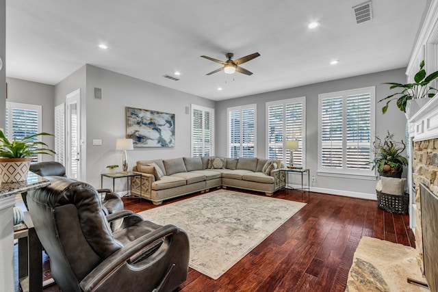 living room with a stone fireplace, ceiling fan, and dark hardwood / wood-style flooring