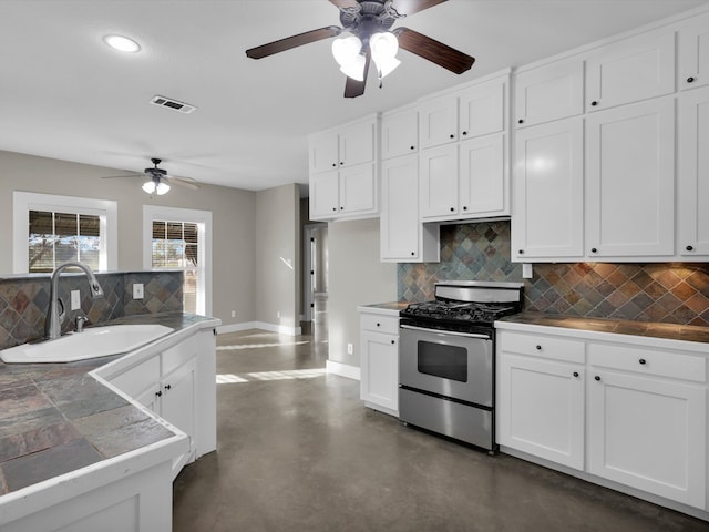 kitchen with backsplash, white cabinetry, stainless steel gas stove, and sink