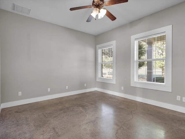 spare room featuring concrete floors, plenty of natural light, and ceiling fan