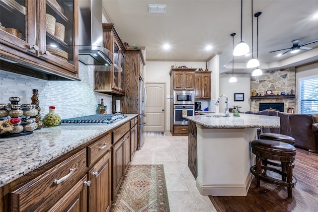 kitchen featuring appliances with stainless steel finishes, decorative backsplash, wall chimney range hood, and pendant lighting