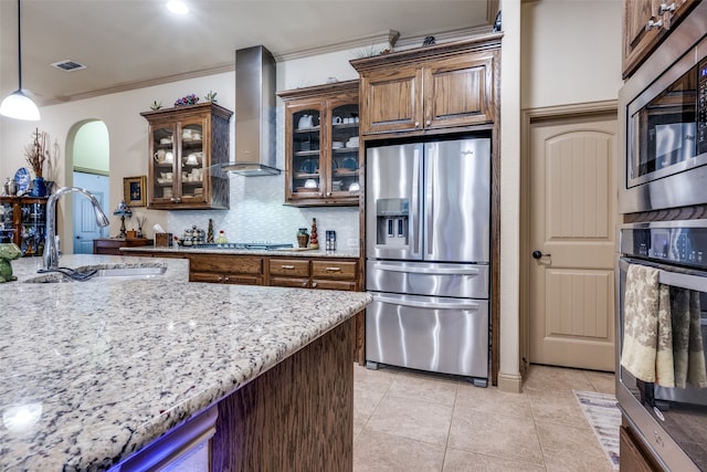 kitchen featuring ornamental molding, sink, pendant lighting, wall chimney exhaust hood, and stainless steel appliances