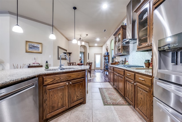 kitchen with hanging light fixtures, sink, crown molding, appliances with stainless steel finishes, and light stone counters