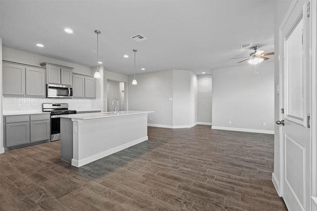 kitchen with hanging light fixtures, dark wood-type flooring, gray cabinetry, and stainless steel appliances