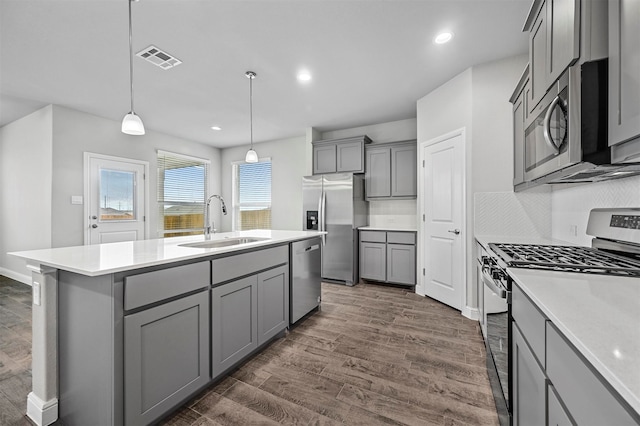 kitchen featuring dark wood-type flooring, a kitchen island with sink, stainless steel dishwasher, and sink